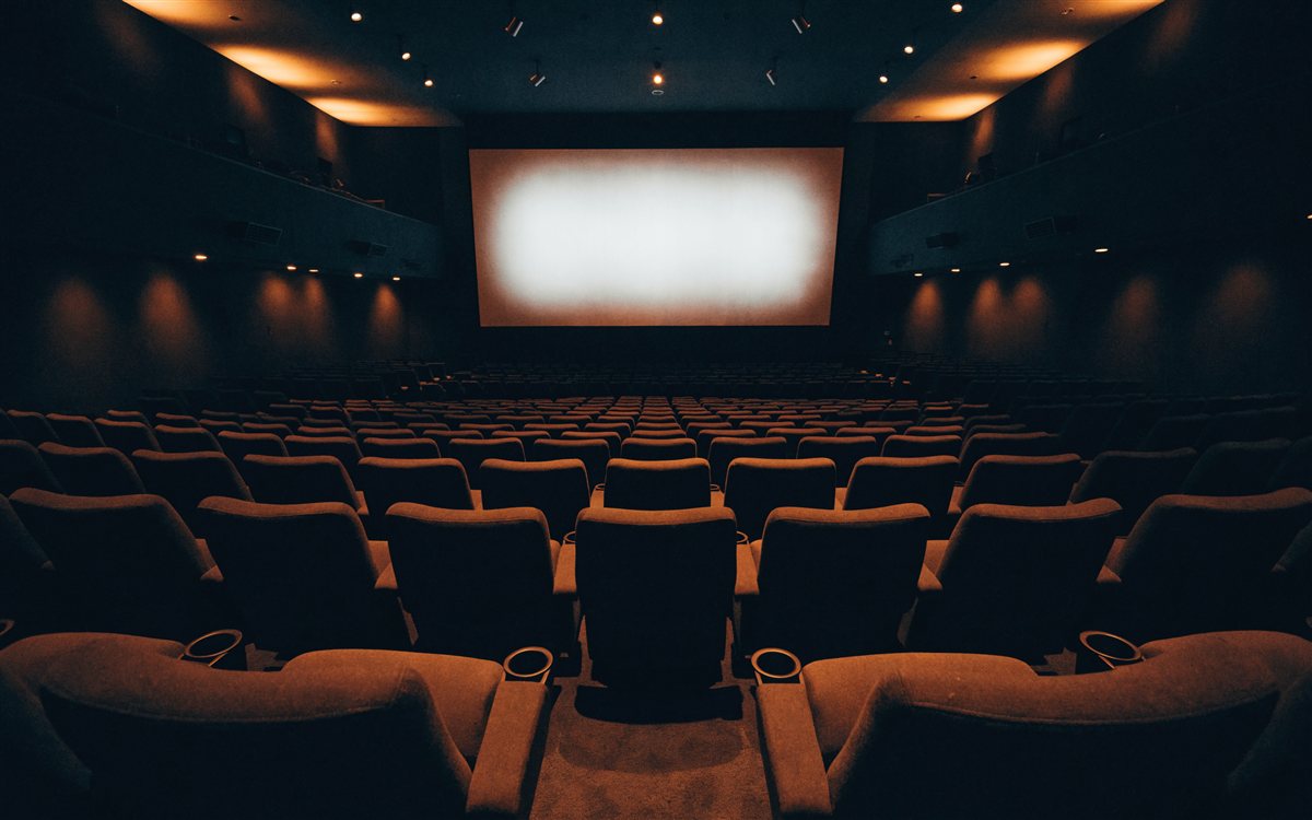 暗い映画館内、座席越しに見える映写中のスクリーン